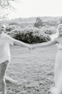 In a blurred black-and-white moment, the couple spins together on the grass, creating a playful and candid scene often seen during an Eolia Mansion wedding day.