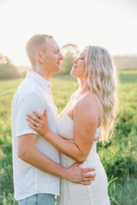 The couple stands close in a sunlit field, sharing a quiet moment as golden light softens the scene, reflecting the natural beauty of an Eolia Mansion wedding setting.