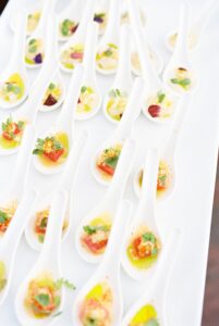 Brooklyn Botanic Garden Wedding | Deirdre Photography Timeless and Organic Moments | Rows of elegant white spoons on a platter hold colorful, bite-sized appetizers. Each spoon features a vibrant mix of herbs, sauce, and small garnishes.