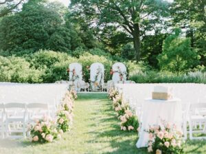 Brooklyn Botanic Garden Wedding | Deirdre Photography Timeless and Organic Moments | Outdoor wedding venue with a lush green backdrop, a central aisle lined with white chairs and pink flowers, leading to an elegant floral altar.