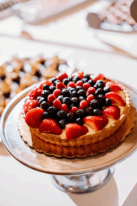 Fresh berry tart displayed on a silver cake stand during an elegant reception with refined details often highlighted in RI wedding photography.