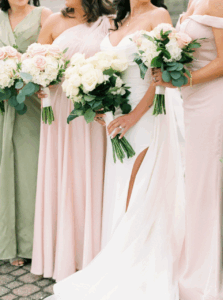 Aldrich Mansion Wedding Photos | Deirdre Photography Timeless and Organic Moments | Bridesmaids in pastel dresses and a bride in a white gown stand holding bouquets of white and pink flowers, conveying a soft, elegant wedding ambiance.
