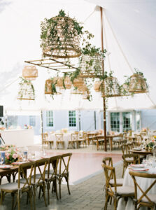 Lion Rock Farm Wedding | Deirdre Photography Timeless and Organic Moments | Elegant outdoor event with rustic charm, featuring wooden tables and chairs under a tent. Hanging wicker baskets with greenery add a natural, festive touch.